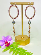 Boho-chic oval hoops featuring sparkling garnets and a bold Tahitian pearl drop.